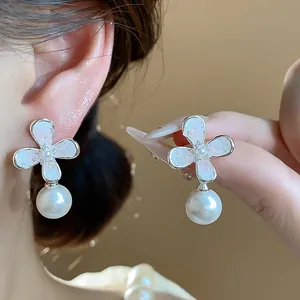 Dettaglio di eleganti orecchini a fiore in argento stile francese con perle bianche pendenti