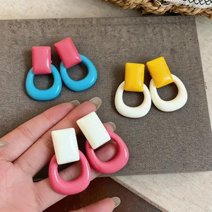 Detailed view of colorful dopamine-style resin geometric earrings on textured mat