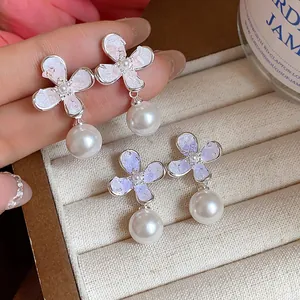 Dettaglio ravvicinato di eleganti orecchini a fiore e perla in stile francese chic