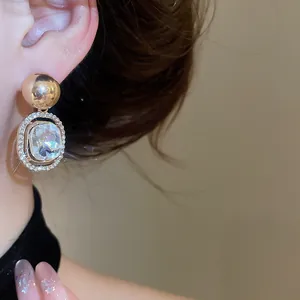 Close-up detail of luxury geometric drop earrings with sparkling rhinestones on model