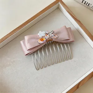 Detailansicht eines rosa Satinschleife Haarkamm mit edlem Strassblumen-Dekor