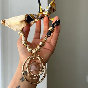 Macro detail of a bohemian resin pendant necklace featuring a printed silk fabric neck strap.