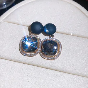 Macro view of geometric stud earrings featuring smoky grey crystals and sparkling halo