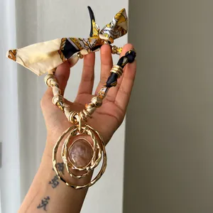 Detailed view of Bohemian style fabric necklace with gold layered resin circular pendant