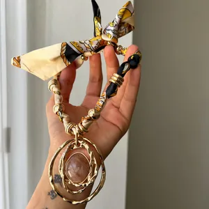Detailed close-up view of a bohemian silk scarf necklace featuring a large golden resin pendant