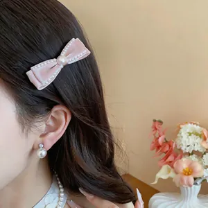 Detailaufnahme einer eleganten rosa Samtschleife mit dekorativen Perlen an einem asiatischen Modell.