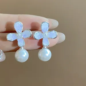 Vista ravvicinata di eleganti orecchini a fiore lavanda con perle bianche pendenti