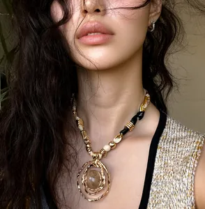 Close-up detail of a vintage-style gold resin circular pendant necklace on a model