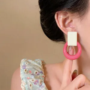 Close-up detail of stylish cream and pink resin geometric earrings worn on an ear.
