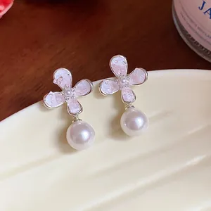 Primo piano di eleganti orecchini con fiori rosa e perle su un piatto di ceramica