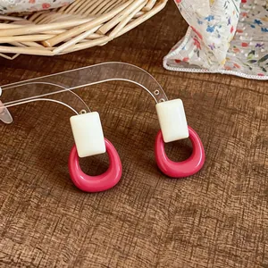 Detailed macro shot of pink resin drop earrings featuring white square tops and silver pins