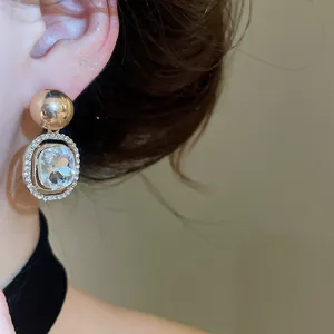 Elegant gold-toned geometric stud earrings with sparkling crystal accents worn on ear