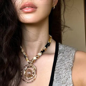 Detailed view of a trendy resin pendant necklace in gold finish worn by a fashion model