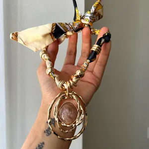Elegant silk scarf necklace featuring a large layered golden ring and resin pendant