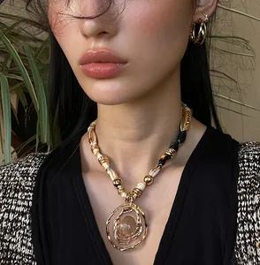 Detailed view of luxury resin pendant necklace and gold earrings on elegant female model
