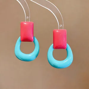 Close-up of vibrant pink and blue resin earrings in a modern geometric design