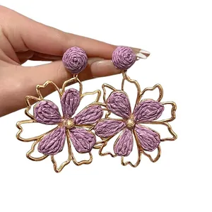Orecchini a fiori traforati in rafia viola fatti a mano con finitura dorata