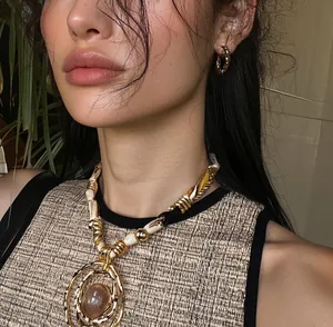 Detailed view of a luxury resin round pendant necklace featuring gold-tone metal wrapping