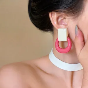 Close-up view of cream square and pink ring resin geometric earrings on an Asian model