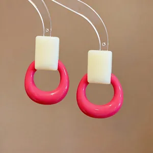 Close-up detail of geometric resin stud earrings in vibrant pink and white dopamine style