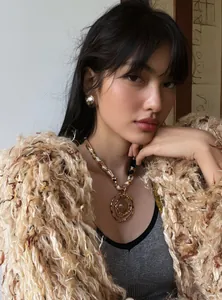 Detail of a chic resin pendant necklace with pearl and gold accents worn by a model.