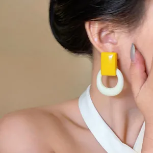 Close-up of a minimalist yellow and cream resin earring worn by a model