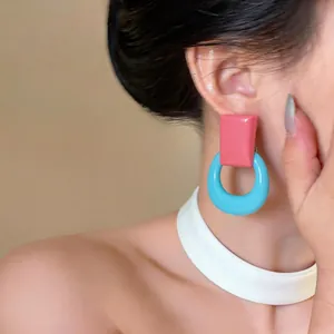 Macro detail view of dopamine-style pink and blue resin earrings worn by a model