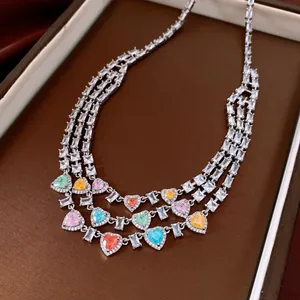 Détail d'un collier de luxe à trois couches avec des pierres en cœur colorées et strass.