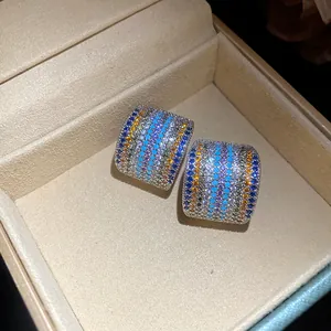 Close-up of vintage square stud earrings with colorful pavé zircons in a beige jewelry box