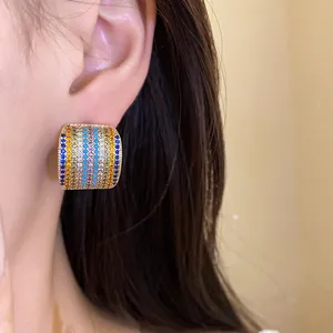 Close-up of a vintage-style square stud earring with multi-colored zircons on model's ear