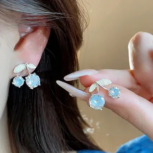 Silver needle cherry zircon stud earrings with blue sparkling stones on model