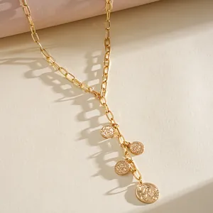 Detailed close-up of gold paperclip chain necklace featuring four vintage coin pendants.