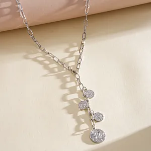 Close-up of retro silver chain necklace with multiple embossed coin pendants and shadows.