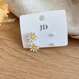 Detailed view of the daisy flower and pearl stud earring set on a white display card