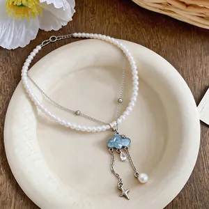 Macro close-up view of elegant blue cloud pendant necklace with pearl and zircon charms