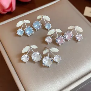 Detail shot of sparkling cherry earrings featuring colorful zircon and white enamel leaves