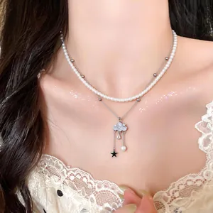 Detail shot of a double-layered necklace featuring a blue cloud pendant and pearls.