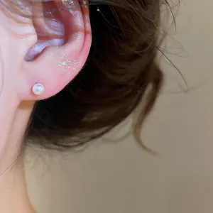 Close-up macro shot of an elegant white pearl stud earring worn on a female earlobe.