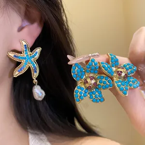 Detailed view of rhinestone starfish and turquoise floral earrings with pearl drop