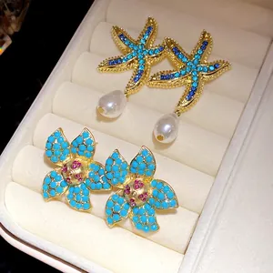 Detailed macro view of elegant starfish pearl and turquoise flower earrings in box