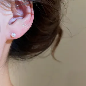 Close-up detail of a minimalist elegant white pearl stud earring worn on the ear