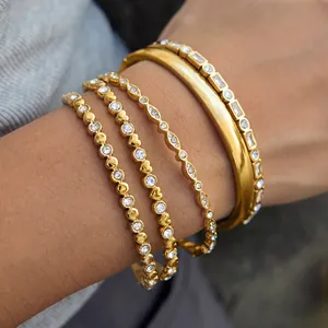 Detail of gold-tone stainless steel bangles set with sparkling rhinestones.