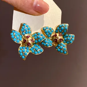 Close-up of starfish flower stud earrings with turquoise beads and pink crystal center