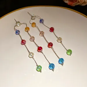 Close-up detail of exquisite three-layer dangling earrings featuring colorful faceted glass beads