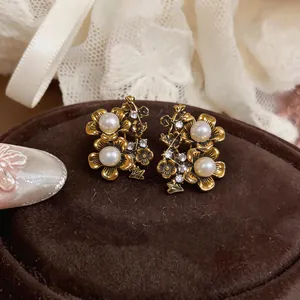 Primo piano di orecchini vintage a fiore dorato con perle eleganti e cristalli lucenti
