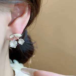 Close-up detail of silver needle cubic zirconia cherry stud earrings on ear for women