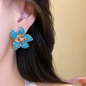 Close-up detail of sea star stud earrings with blue beads and pink rhinestone center
