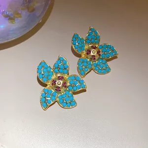 Detailed view of gold-tone starfish earrings featuring turquoise beads and pink crystals