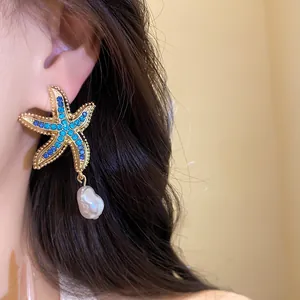 Close-up of blue rhinestone starfish earring with a dangling baroque pearl drop