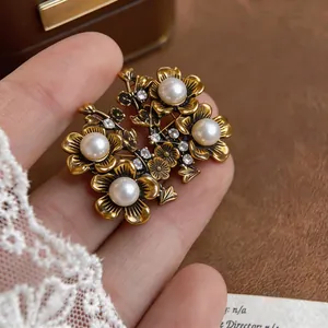 Dettaglio di orecchini a fiore in oro vintage con perle e piccoli cristalli.